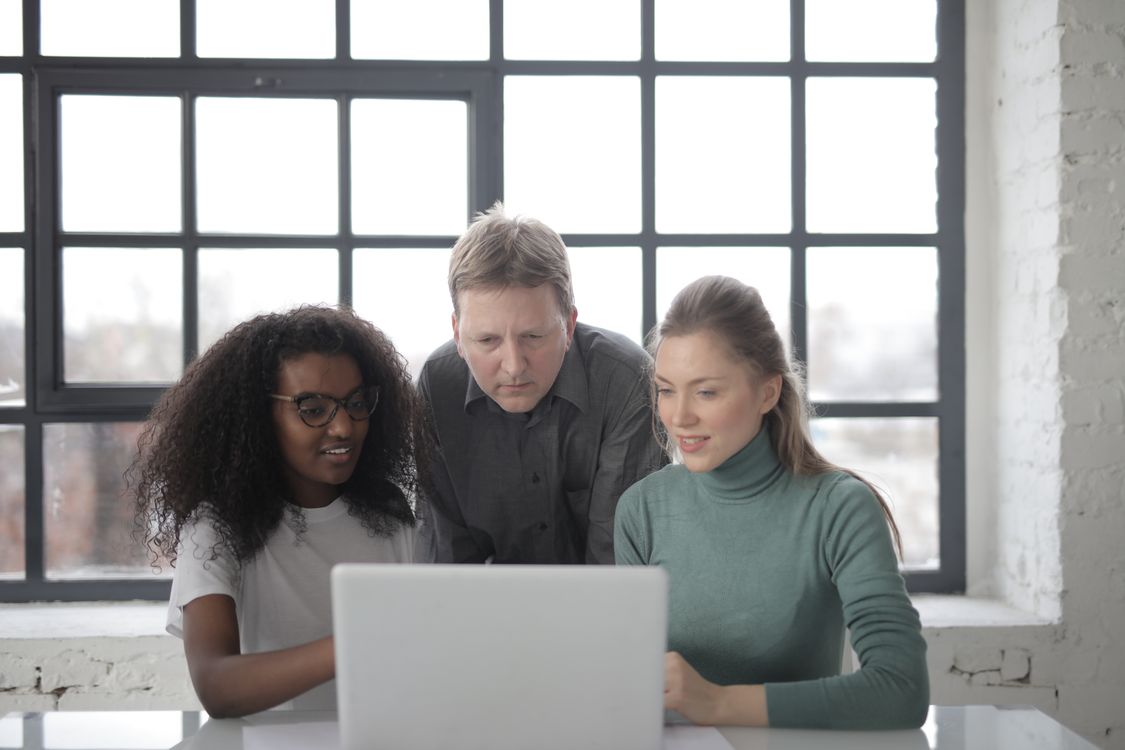 Adult colleagues working together around a laptop
